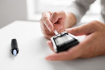 Image showing senior man with glucometer checking blood sugar