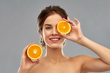 Image showing smiling woman with oranges over grey background