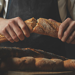 Image showing organic delicious baguette halves in the hands of man