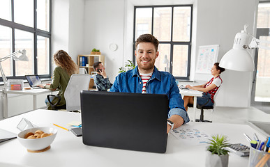 Image showing smiling creative man with laptop working at office