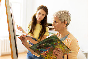 Image showing senior woman painting at art school studio