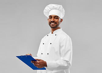 Image showing happy male indian chef in toque with clipboard