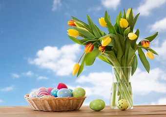 Image showing colored easter eggs in basket and flowers