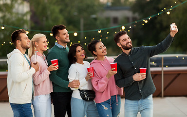 Image showing friends with drinks taking selfie at rooftop party