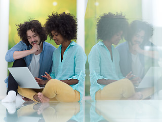 Image showing multiethnic couple using a laptop on the floor