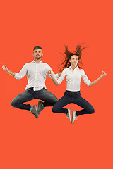 Image showing Freedom in moving. Pretty young couple jumping against red background