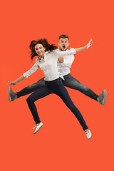 Image showing Freedom in moving. Pretty young couple jumping against red background