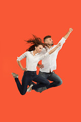 Image showing Freedom in moving. Pretty young couple jumping against red background