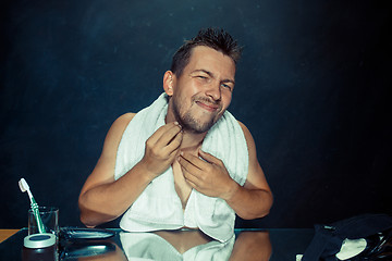 Image showing Close up photo of young man looking for acnes on his face