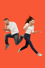 Image showing Full length of young couple with mobile phone while jumping