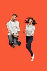 Image showing Freedom in moving. young couple jumping against red background