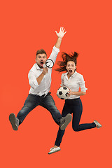 Image showing The young man and woman as soccer football players kicking the ball at studio