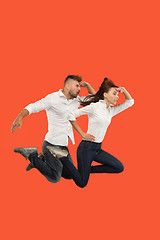 Image showing Freedom in moving. Pretty young couple jumping against red background