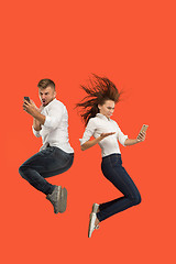 Image showing Full length of young couple with mobile phone while jumping