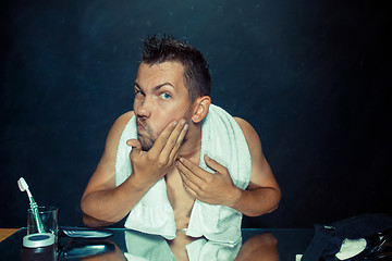 Image showing Close up photo of young man looking for acnes on his face