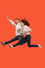 Image showing The young man and woman as soccer football players kicking the ball at studio