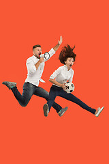 Image showing The young man and woman as soccer football players kicking the ball at studio