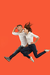 Image showing Freedom in moving. Pretty young couple jumping against red background