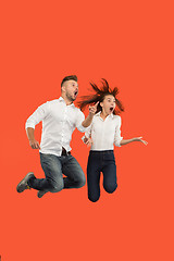 Image showing Freedom in moving. Surprised young couple jumping against red background