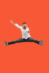 Image showing Freedom in moving. handsome young man jumping against orange background