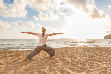 Image showing Woman practicing yoga on sea beach at sunset.