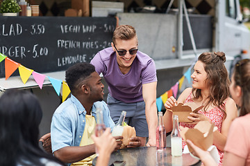 Image showing happy friends with drinks eating at food truck