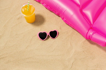 Image showing sunglasses, juice and pool mattress on beach sand