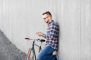 Image showing hipster man in earphones with smartphone and bike