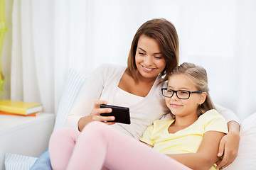 Image showing happy mother and daughter with smartphone at home