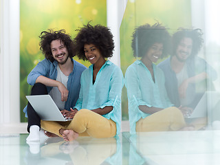 Image showing multiethnic couple using a laptop on the floor