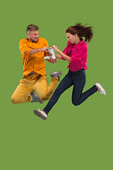 Image showing Beautiful young couple jumping with megaphone isolated over green background