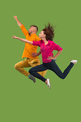 Image showing Freedom in moving. Pretty young couple jumping against green background