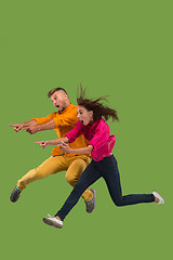 Image showing Freedom in moving. Pretty young couple jumping against green background