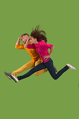 Image showing Freedom in moving. Pretty young couple jumping against green background