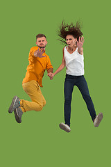 Image showing Freedom in moving. Pretty young couple jumping against green background