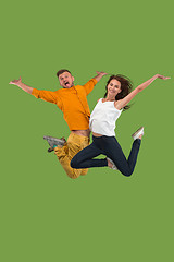 Image showing Freedom in moving. Pretty young couple jumping against green background