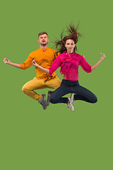Image showing Freedom in moving. Pretty young couple jumping against green background
