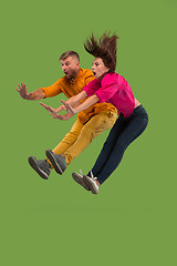 Image showing Freedom in moving. Pretty young couple jumping against green background