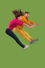 Image showing Freedom in moving. Pretty young couple jumping against green background