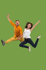 Image showing Freedom in moving. Pretty young couple jumping against green background