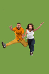 Image showing Freedom in moving. Pretty young couple jumping against green background