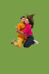 Image showing Full length of young couple with mobile phone while jumping