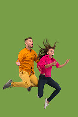 Image showing Freedom in moving. Pretty young couple jumping against green background