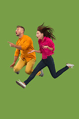 Image showing Freedom in moving. Pretty young couple jumping against green background