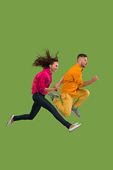 Image showing Freedom in moving. Pretty young couple jumping against green background