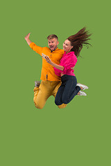 Image showing Full length of young couple with mobile phone while jumping