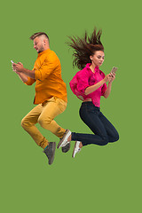 Image showing Full length of young couple with mobile phone while jumping