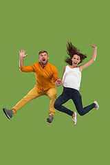 Image showing Freedom in moving. Pretty young couple jumping against green background