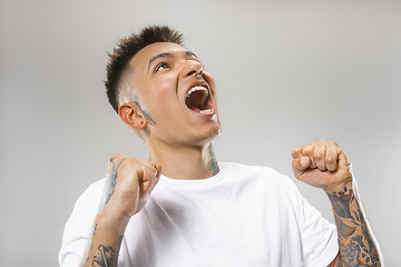 Image showing The young emotional angry man screaming on gray studio background