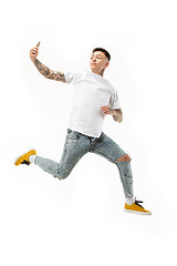 Image showing Full length of handsome young man taking selfie while jumping